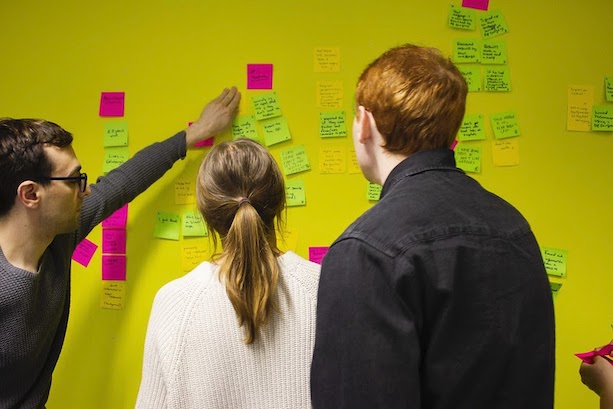 People looking at post-it notes on the wall during a GDS workshop