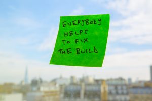 A sticky note reads "Everybody helps to fix the build".