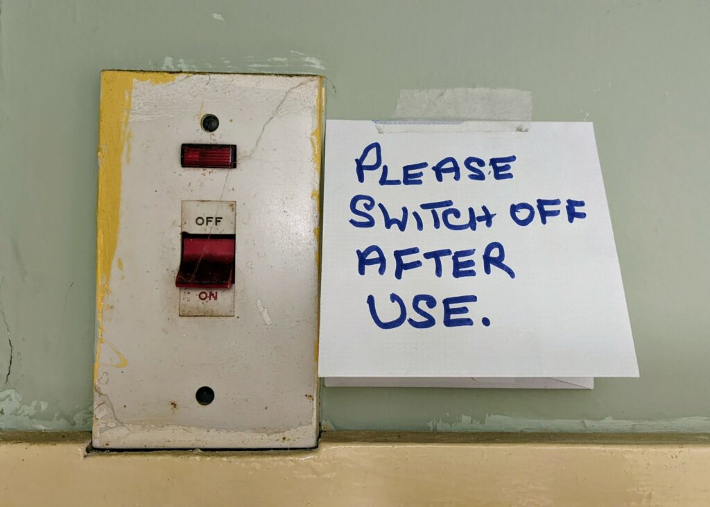 Image of plug socket with post it saying 'please switch off after use'